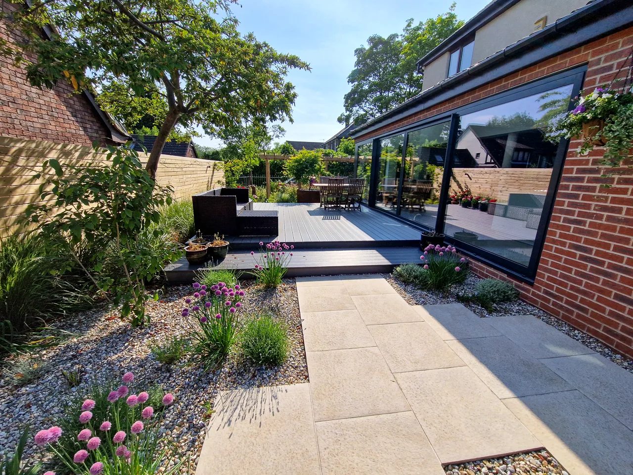 Contemporary garden design - A raised wood-composite deck outside large sliding patio doors in Alwoodley. Yorkshire Gardens, Leeds