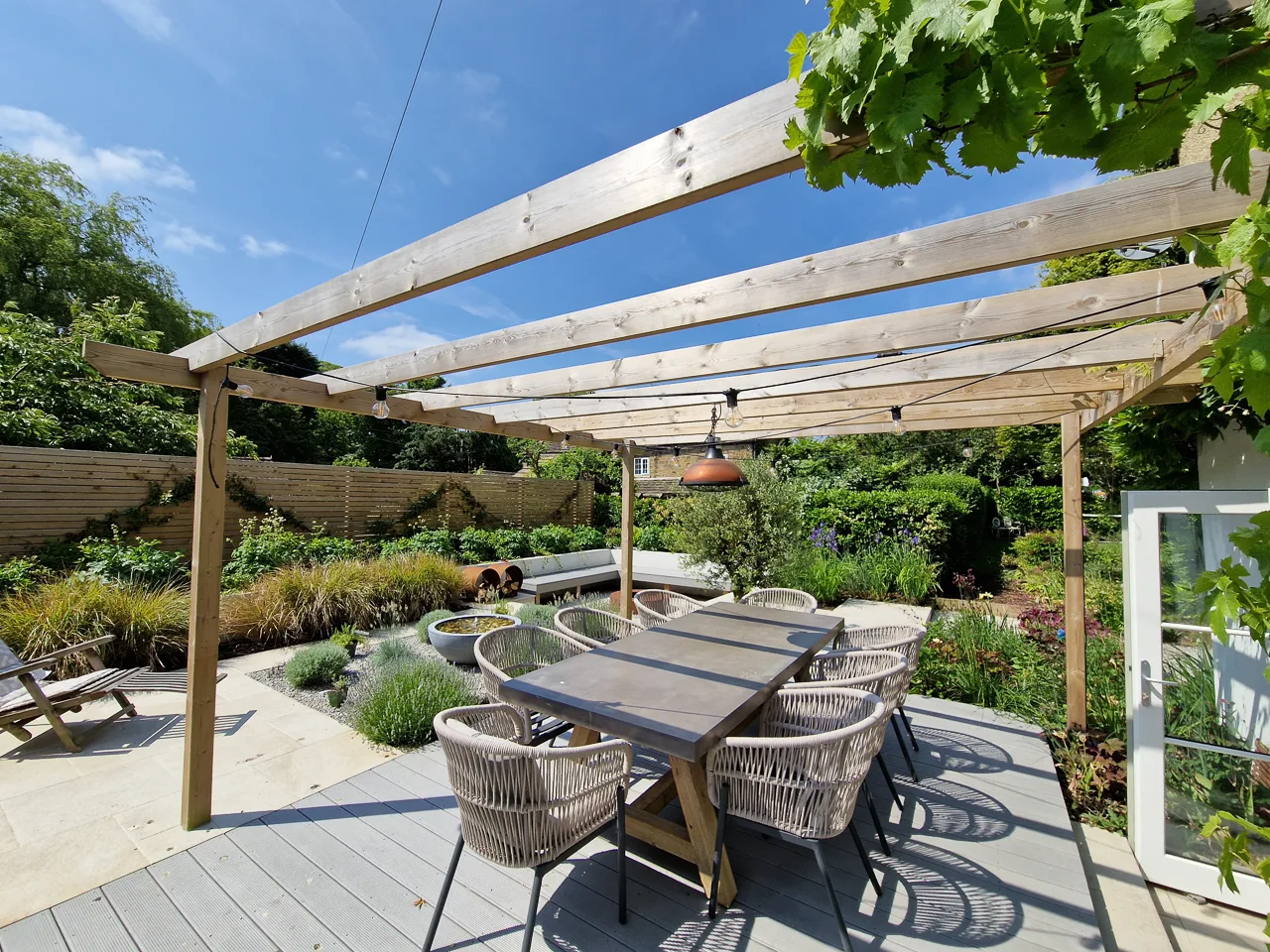 Contemporary garden design - Pergola with grape vine over a wood-composite deck. Dining area in OultonYorkshire Gardens, Leeds