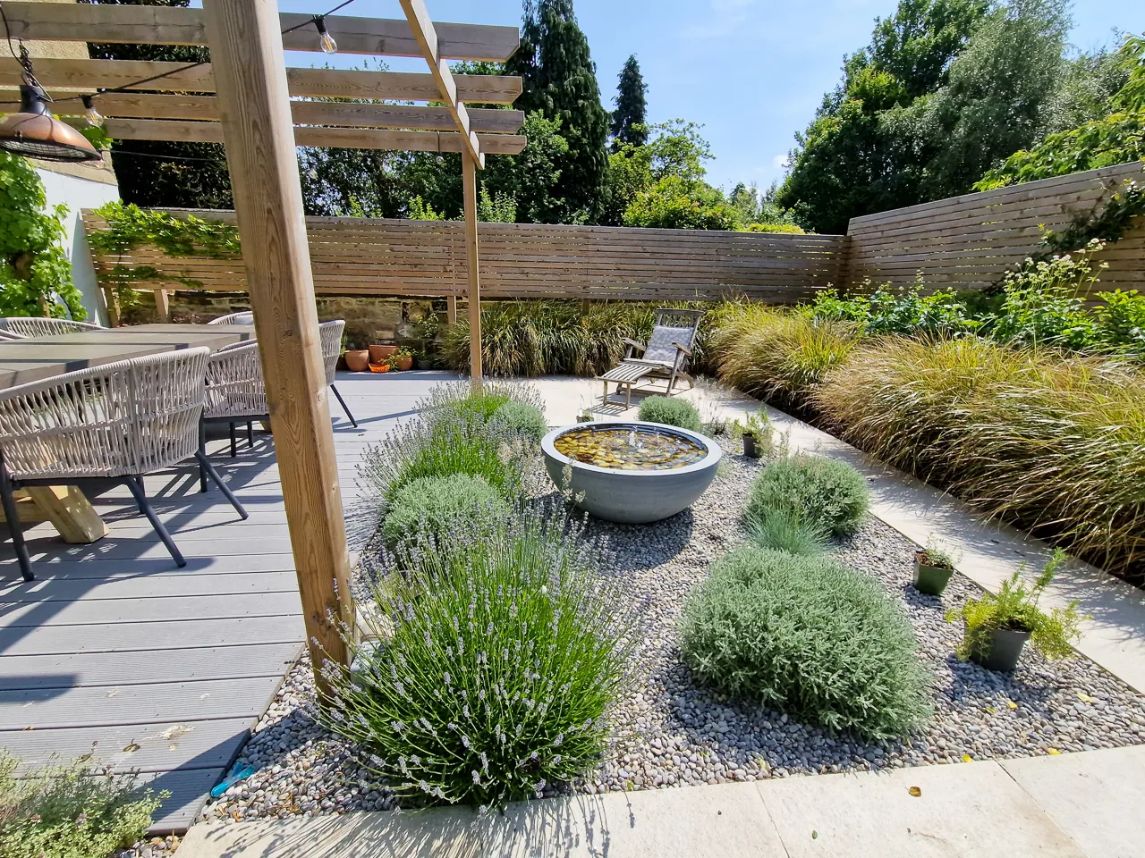 Contemporary garden design - Courtyard garden with water feature, pergola and easy chair in Oulton. Yorkshire Gardens, Leeds